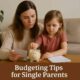 Single mother teaching her child about saving money with a piggy bank at home – budgeting tips for single parents